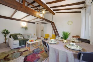 A cozy living room with a sofa, coffee table, and a dining area set for a meal. - Cosy Joffre - loft et mezzanine, Croisette à 5 min (Cannes)