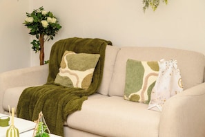 A beige sofa with a green throw blanket and two patterned throw pillows. - Cosy Joffre - loft et mezzanine, Croisette à 5 min (Cannes)