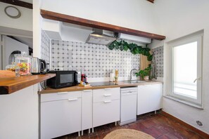 A compact kitchen with white cabinets, a microwave, a coffee maker, and a sink. - Cosy Joffre - loft et mezzanine, Croisette à 5 min (Cannes)