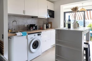 A compact kitchen with a washing machine, a microwave, and a coffee maker. - Cala Bianca - Cocon familial vue mer, 6 personnes (Bormes-les-Mimosas)