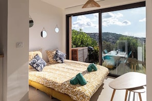 A bedroom with a large bed, a balcony with a table and chairs, and a view of the outdoors. - Cala Bianca - Cocon familial vue mer, 6 personnes (Bormes-les-Mimosas)