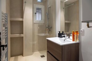 Ein modernes Badezimmer mit Dusche, Spiegel und Waschbecken mit Pflegeprodukten.
