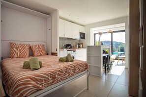 Ein modernes Hotelzimmer mit Bett, einer Küchenzeile und einem Balkon mit Blick.
