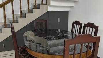 Un comedor con una mesa redonda, seis sillas y una escalera con barandilla de madera.