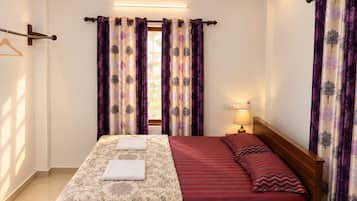 Une chambre d’hôtel avec un lit, une lampe de chevet et des rideaux à motifs floraux.