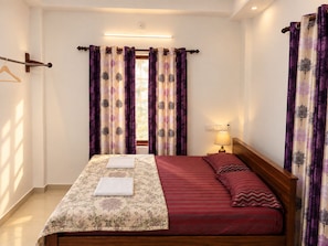 Ein Hotelzimmer mit einem Bett, einer Nachttischlampe und Vorhängen mit einem Blumenmuster.