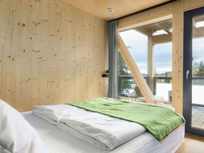 Ein Schlafzimmer mit Bett, Fenster und Blick ins Freie.