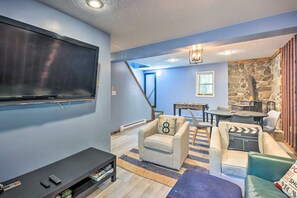 A living room with a flat-screen TV, a sofa, a coffee table, and a foosball table. - Pocono Cabin w/ Fire Pit, Kayaks & Lake Access (Big Bass Lake)
