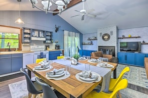 Une cuisine moderne avec des meubles bleus, un coin repas avec des chaises jaunes et une cheminée.