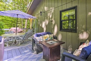 Une terrasse extérieure couverte, aménagée avec une table, des chaises et une petite table d’appoint décorative.