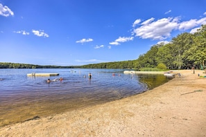 Un lac aux eaux cristallines, une plage de sable et des bateaux.