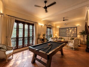 A pool table in a well-lit room with a ceiling fan, comfortable seating, and a large framed picture of a saxophone. - Private West Lake Pool Villa 7Brs by Anamoi (Hà nội)