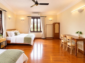 Habitación de hotel con cama, mesita de noche, armario y mesa de comedor con sillas.