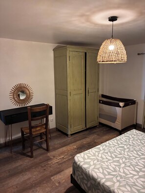 Une chambre à coucher comprenant un lit, un bureau, une chaise, une armoire et un luminaire suspendu.