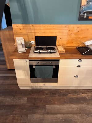Une petite cuisine équipée, avec une cuisinière et un four intégrés, ainsi qu’un petit plan de travail.
