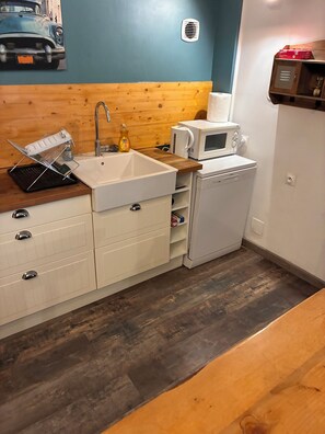 A compact kitchen with a sink, microwave, and dishwasher, wooden countertop, and a wall-mounted heater. - Family home in Tarascon in the countryside: walks, relaxation, and a warm, friendly atmosphere  (Tarascon)