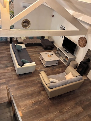 Un salon moderne avec un canapé d’angle, un téléviseur à écran plat et une cheminée.