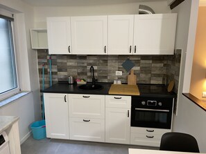A compact kitchen with white cabinets, a black sink, and a built-in oven. - Casa dei Fregoso | Cozy apartment, 5 minutes from the aquarium (Genova)