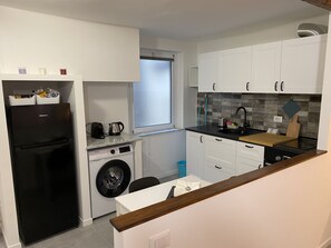 A compact kitchen with a washing machine, a refrigerator, and a window. - Casa dei Fregoso | Cozy apartment, 5 minutes from the aquarium (Genova)