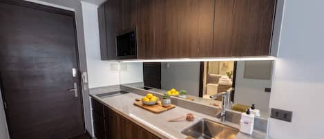 A modern kitchen with a built-in microwave, a stainless steel sink, and a wooden countertop.