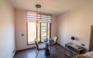 A modern hotel room with a dining area, a bed, a bedside table with a lamp, and a view of the outside. - Espacio Huerfanos by Domus Travels (Santiago)