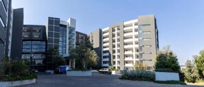 A modern multi-story building with a parking area in front. - Imperial Ventures Apartments - 1 BR apt 2 (Sandton)