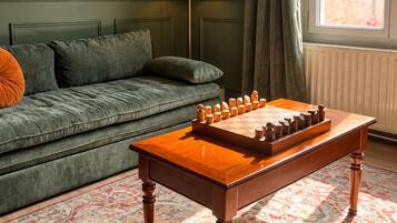 A room with a sofa, a wooden table with a checkered game, and a patterned carpet.