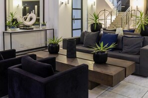 Una sala de estar moderna con un sofá, sillones, una mesa de centro y plantas en macetas.