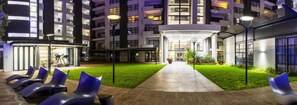 Un patio de hotel con un camino central, mobiliario exterior y un área de fitness.
