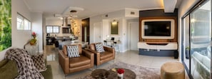 A modern living room with a sofa, coffee table, and a flat-screen TV mounted on the wall. - Imperial Ventures Apartments - 1 BR apt (Sandton)