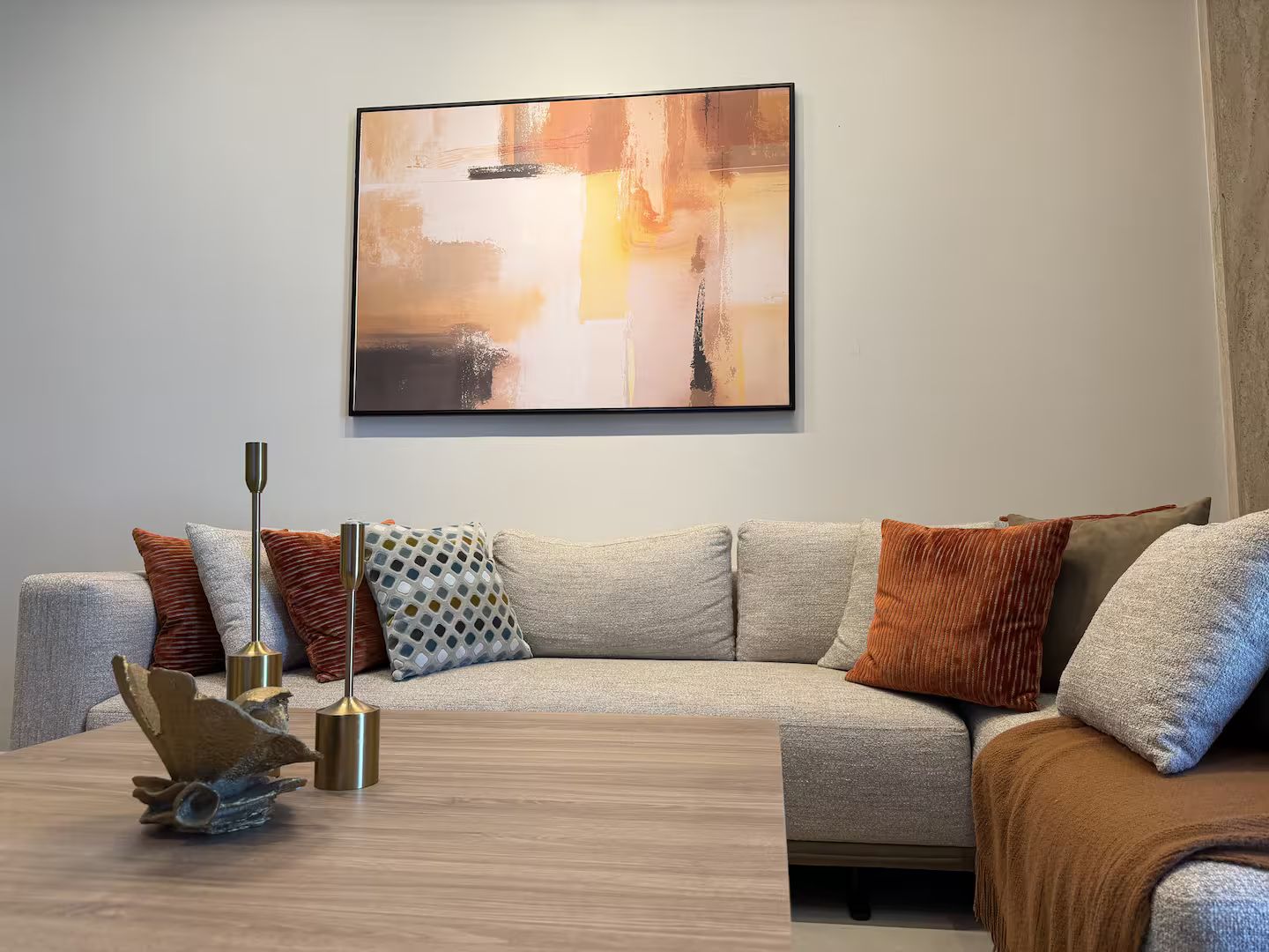 A modern living room with a sectional sofa, a coffee table, and a large abstract painting on the wall.