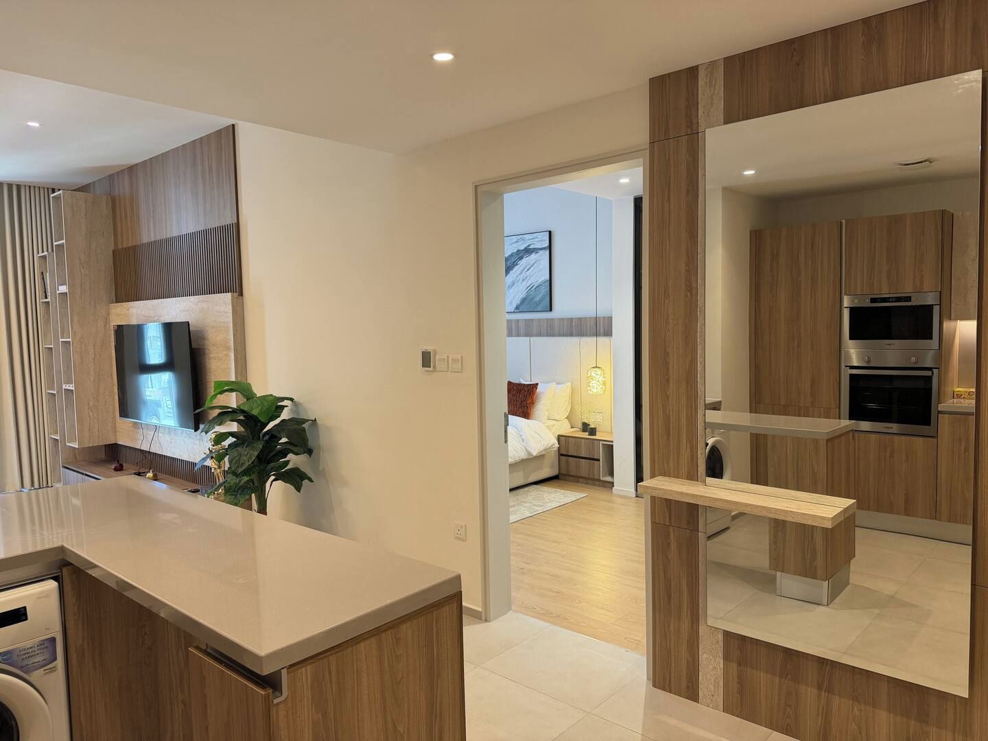 A modern kitchen with built-in appliances, a flat-screen TV, and a bench.