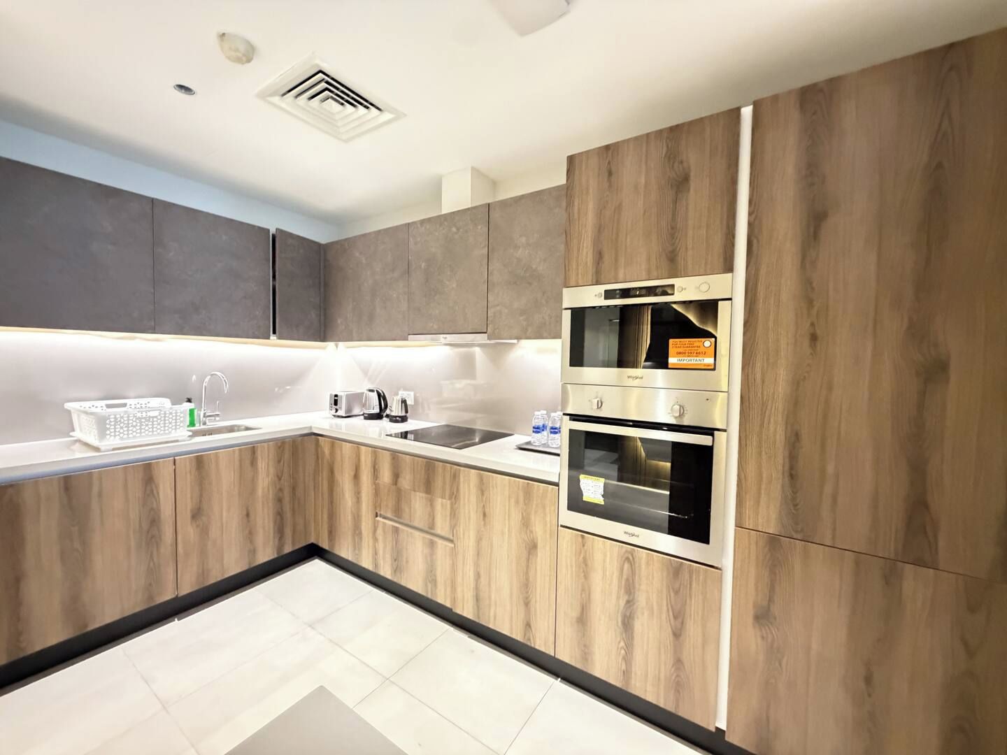 A modern kitchen with wooden cabinets, stainless steel appliances, and a white countertop.