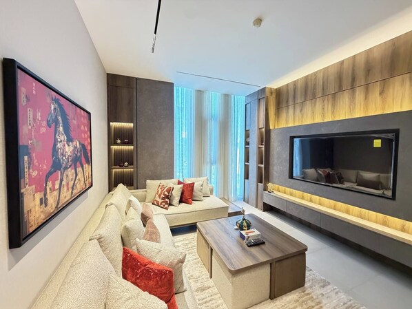 Una sala de estar moderna con un sofá modular, una mesa de centro y un televisor montado en la pared.