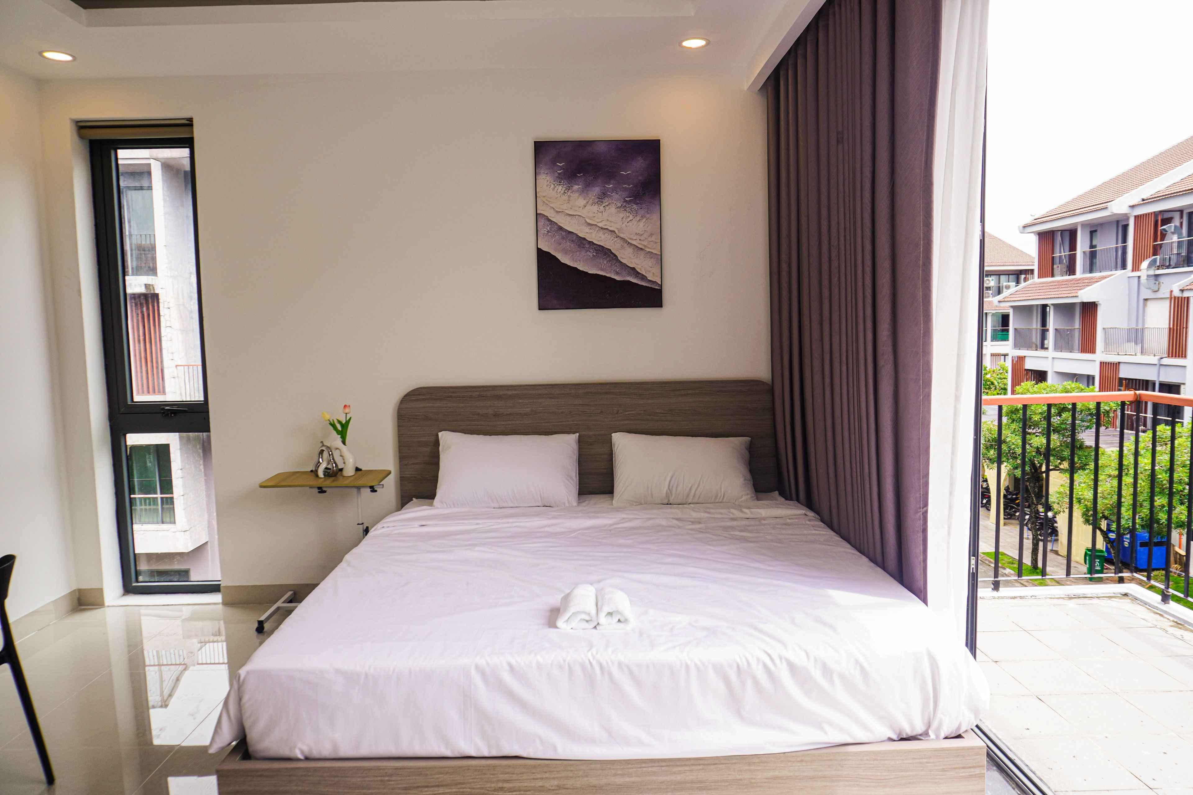 Een hotelkamer met een groot bed, een nachtkastje, een schilderij en uitzicht op het omliggende landschap.