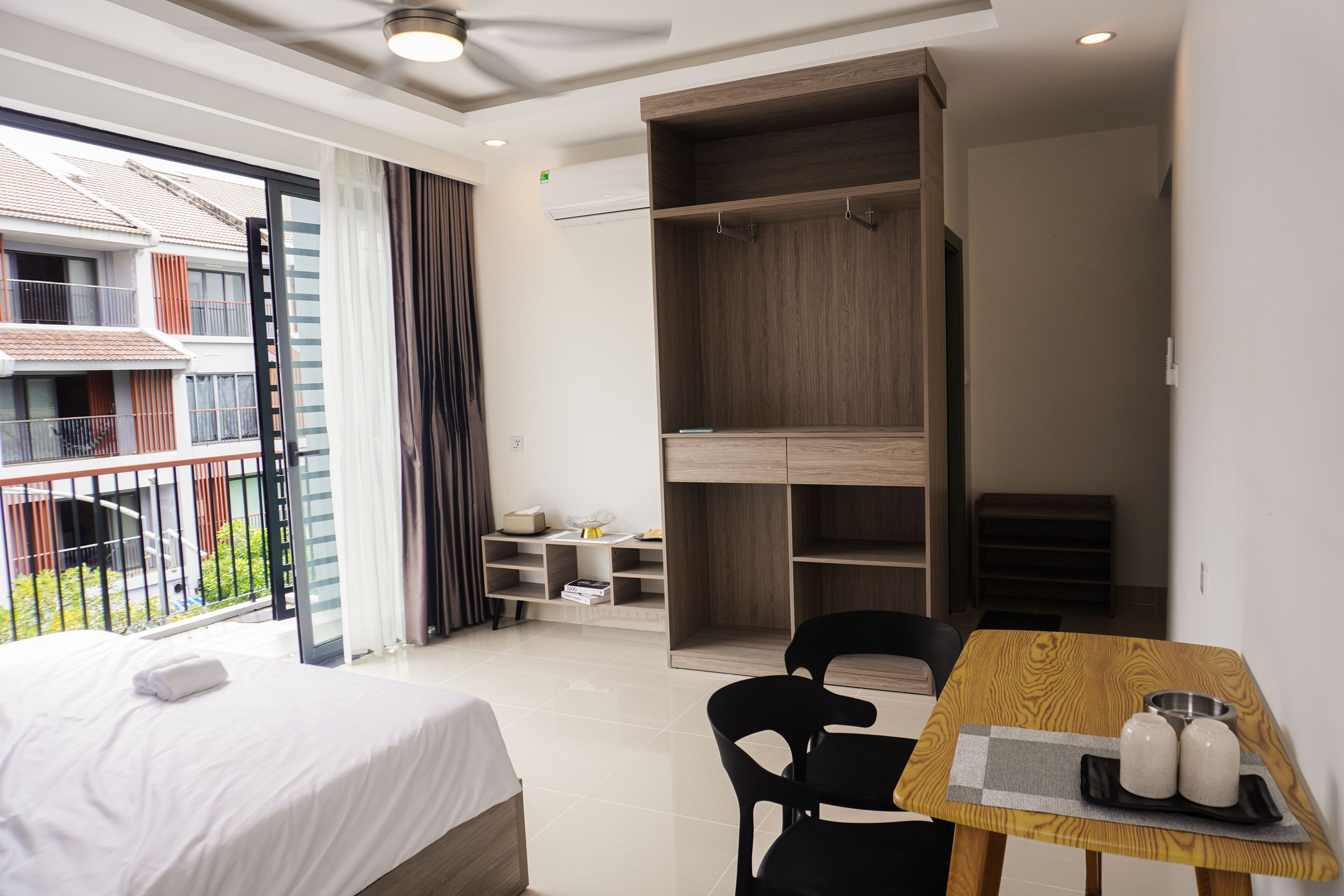 Ein Hotelzimmer mit Bett, Schreibtisch mit Stühlen, kleinem Tisch und Wasserflasche sowie Blick auf den Balkon.