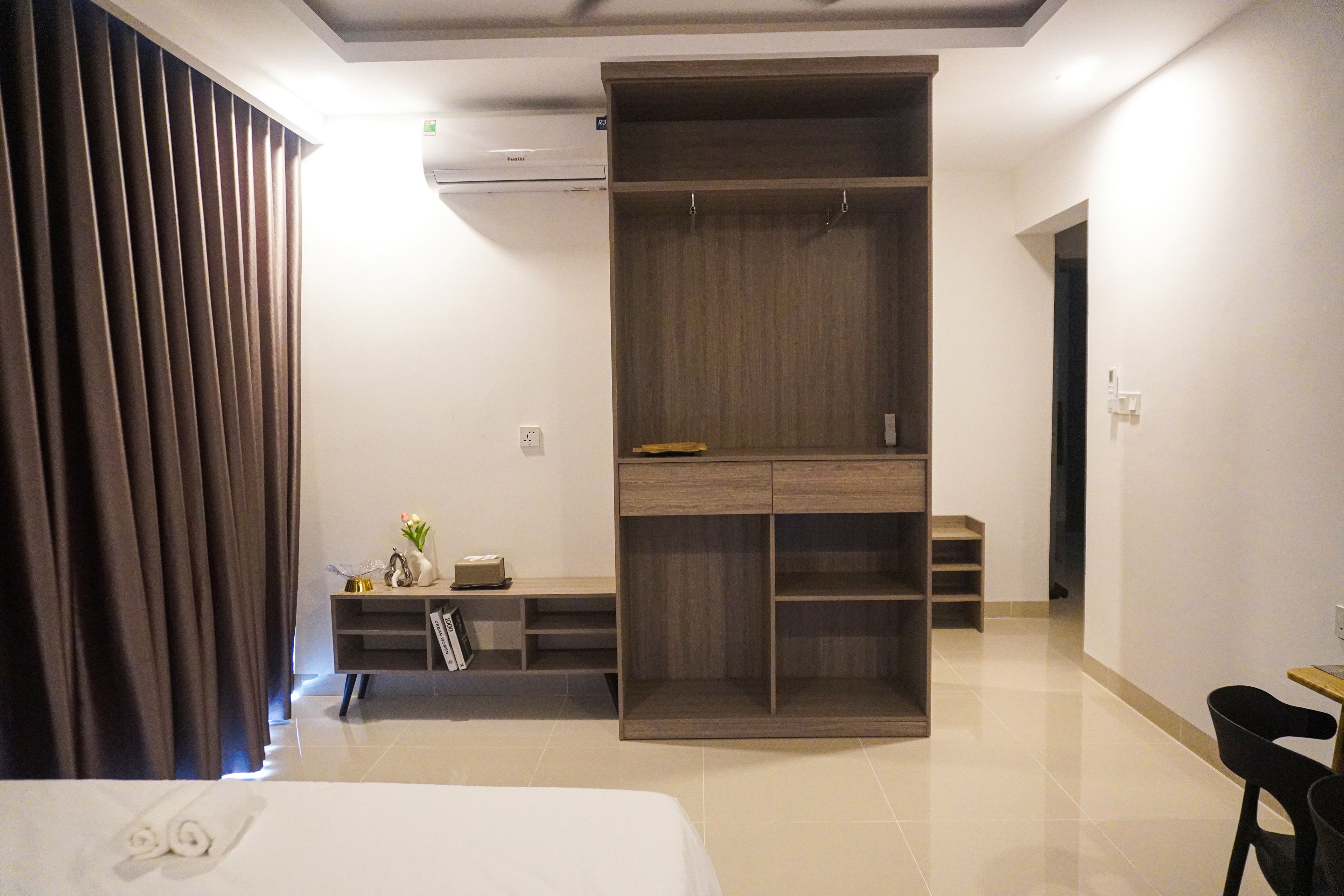 Ein Hotelzimmer mit einem Bett, einem Kleiderschrank, einem Schreibtisch mit Stuhl und einem kleinen Tisch.