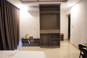 Ein Hotelzimmer mit einem Bett, einem Kleiderschrank, einem Schreibtisch mit Stuhl und einem kleinen Tisch.