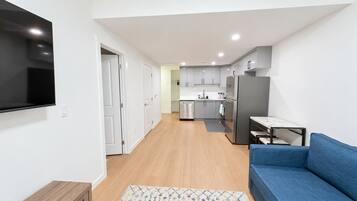 A modern kitchen with grey cabinets, a stainless steel refrigerator, and a built-in oven.