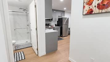 A modern kitchen with grey cabinets, a stainless steel refrigerator, and a wooden floor.