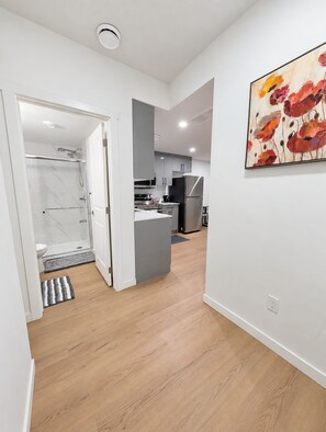 A modern kitchen with grey cabinets, a stainless steel refrigerator, and a wooden floor. - Cozy Private Suite | Near WEM | No Cleaning Fee (Edmonton)