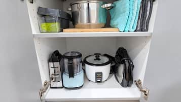 A kitchen with a built-in oven, a slow cooker, a rice cooker, and a pot on the countertop.