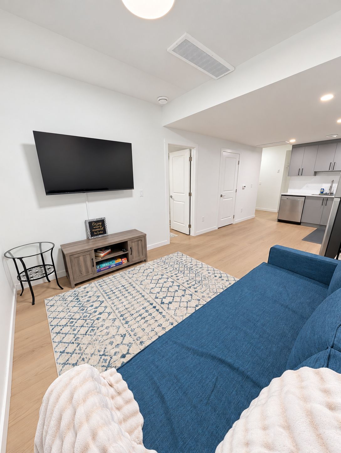 A modern living room with a flat-screen TV, a sofa, a coffee table, and a rug.