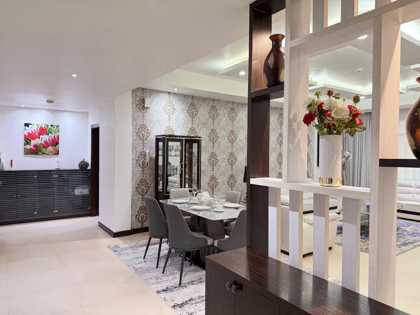 Un comedor moderno con una mesa redonda, sillas grises y un aparador decorativo.