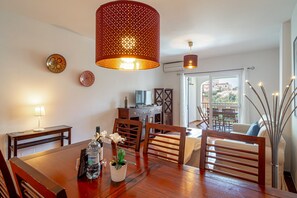 A dining area with a wooden table, chairs, a potted plant, and a television on a stand. - Holiday Home in Nerja With Sea Views (Nerja)