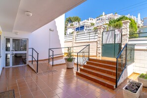 A residential property with a tiled patio, a staircase with metal railings, and a view of a white building in the background. - Holiday Home in Nerja With Sea Views (Nerja)
