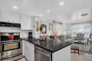 A modern kitchen with stainless steel appliances, a black granite countertop, and white cabinetry. - Award-Winning Resort Amenities | Port O' Call A204 (Isle Of Palms)