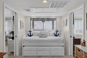 A bedroom with a bed, built-in drawers, a ceiling vent, and a window with blinds. - Award-Winning Resort Amenities | Port O' Call A204 (Isle Of Palms)