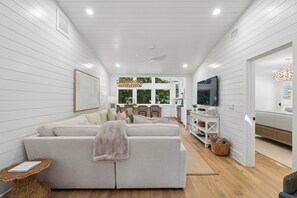Un salon moderne comprenant un canapé, un téléviseur et un coin repas avec des chaises et une table.