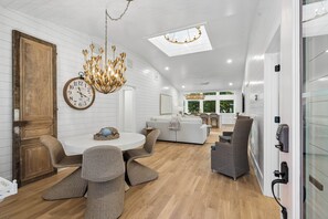 Un intérieur moderne avec un coin repas, un lustre et une horloge.
